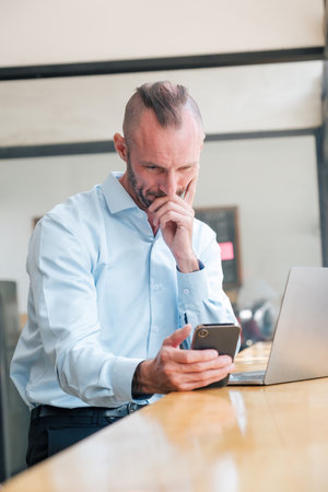 Young Caucasian businessman using smartphone explore the world of social media and laptop while...