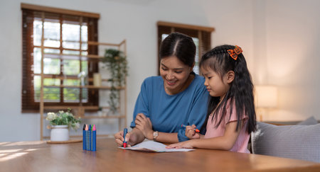 Happy family mother and daughter study or draw together at home in living roomの写真素材