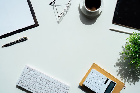 Top view above of white office desk table with keyboard computer, notebook and coffee cup with equipment other office supplies. business and finance concept. workplace, flat lay with blank copy spaceの写真素材