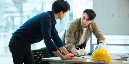 Engineer team with construction work plan discussion together blueprint on working table in construction site with safety helmetの写真素材