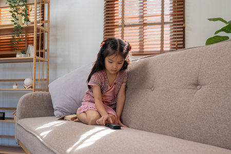 Asian little girl sitting on sofa at homeの写真素材