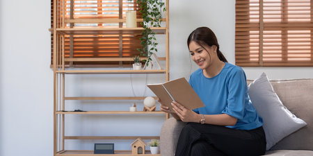 Young asian woman relax casualwear sit on sofa and read bookの写真素材
