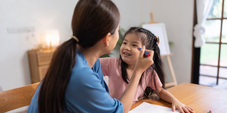 Happy family mother and daughter study or draw together at home in living roomの写真素材
