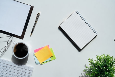 Top view above of white office desk table with keyboard computer, notebook and coffee cup with...