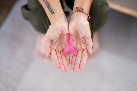 Elder woman hand holding pink ribbon symbol. Breast cancer awareness and october pink day, world cancer day, national cancer survivor day. healthcare conceptの写真素材