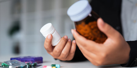 Woman hold bottle of drug tablet painkiller or vitamin supplement reading label ready to organizing medicine at home. medication healthcare conceptの写真素材