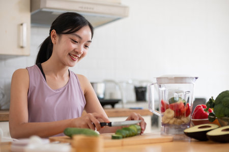 Young Asian healthy beautiful woman with casual clothes is smile and slicing fresh fruit to diet at home in kitchen in holidayの写真素材
