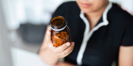 Woman hold bottle of drug tablet painkiller or vitamin supplement reading label ready to organizing medicine at home. medication healthcare conceptの写真素材