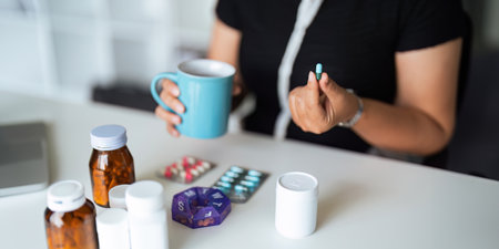 Close up woman holding pill in hand with water feeling sick. female going to take painkiller from headache, painkiller, healthcare, medicine, treatment, therapy, patient, disease illness conceptの写真素材