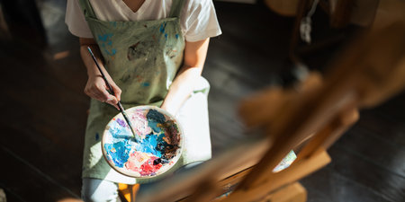 Close up of a creativity young woman artists hands painting vibrant strokes on a canvas in artistic process in workshopの写真素材