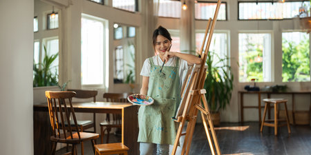 Beautiful Asian creativity woman artist smiling confident painting on canvas at art studioの写真素材
