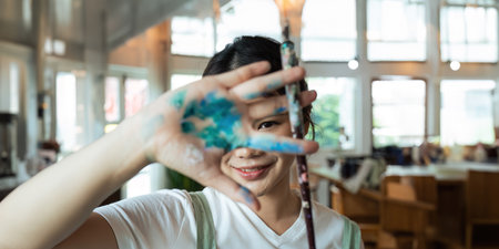 The artist creates a frame with his hands soiled with poster color paints. Portrait of a young...
