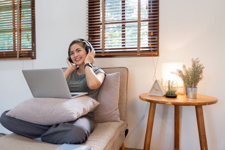Asian beautiful woman smile at home in headphones. young woman listen music at home. Use technology, lifestyle conceptの写真素材
