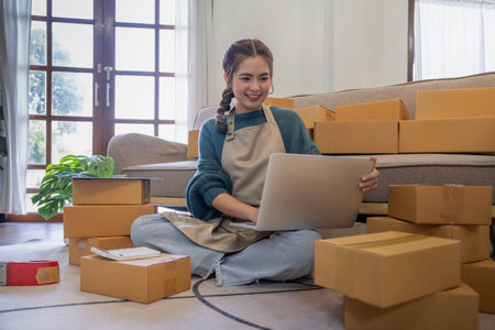 Young woman working online ecommerce shopping at her shop. Young woman seller prepare parcel box of...