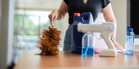 Asian woman cleaning in work room at home. Young woman housekeeper cleaner use feather duster wiping...