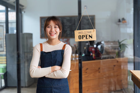 Asian woman barista holding tablet for checking order from customer on blurred coffee cafe shop background , SME business conceptの写真素材