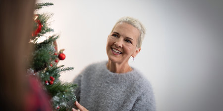 Cheerful elderly woman decorat the christmas tree. Christmas atmosphere at cozy home interiorの写真素材