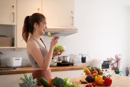 Young woman eat healthy food sitting in the kitchenの写真素材