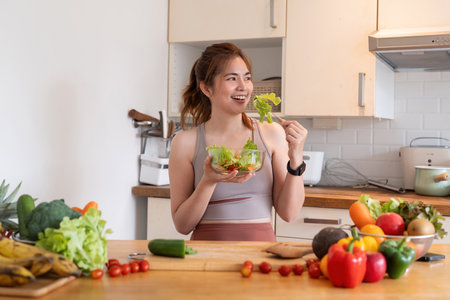 Young woman eat healthy food sitting in the kitchenの写真素材