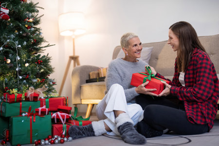 Family winter holiday and concept happy mother and daughter decorate christmas tree and give a gift at homeの写真素材