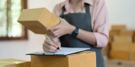 Asian woman entrepreneur prepare parcel box and check online order on laptop computer for commercial checking delivery. online marketing, packing box, SME seller. startup business conceptの写真素材