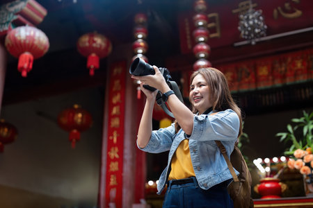 Young beautiful woman asian in market and took her camera up take a photo. woman tourist with camera...