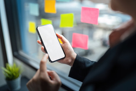 Business woman hand holding using mockup mobile phone with white blank screen for text, mobile app design and advertising, online marketingの写真素材