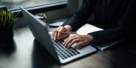 Close up Asian business woman using laptop to calculate tax and financial data of business at officeの写真素材