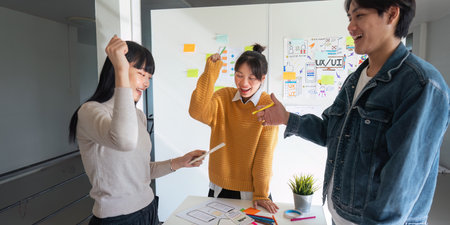 Ux developer and Ui designer successful creative in smart casual wear discussing phone application design celebrate giving five after dealing feeling happy in officeの写真素材