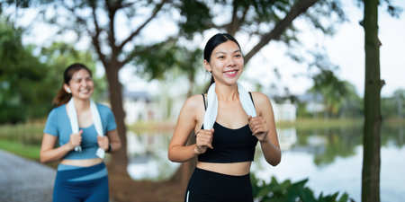 Jogging woman running in park on beautiful day off. Sport fitness model of asian ethnicity training outdoor for marathonの写真素材