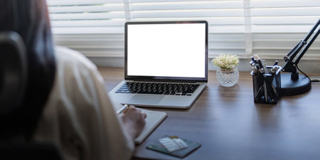Laptop screen mock up, laptop in blank empty screen on the desk in home while woman working on financial calculatingの写真素材