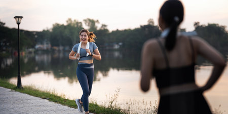 Jogging woman running in park on beautiful day off. Sport fitness model of asian ethnicity training outdoor for marathonの写真素材