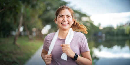 Young smiling sporty woman running in park in the morning. Fitness girl jogging in parkの写真素材