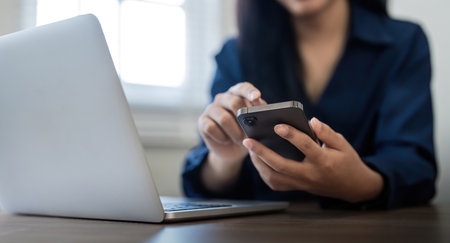Young business woman on the phone at office. Business woman texting on the phone and working on laptop. Pretty young business woman sitting on workplaceの写真素材