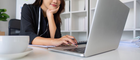 Businesswoman working using laptop computer to record and print information for a marketing plan...