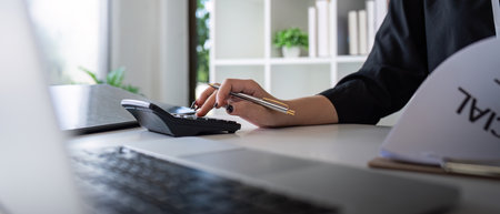 Businesswoman accountant using calculator and laptop for financial data saving in office room, Business financial, tax, accounting conceptの写真素材