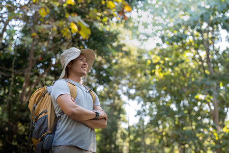 Young man asian trekking among trees with backpack, young man enjoy alone in forest. Camping,...