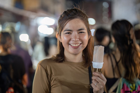 Happy young beautiful woman eating a traditional thai ice cream in the street foodの写真素材