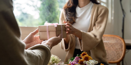 Romantic young asian couple embracing giving present in living room at home. Fall in love. Valentine...