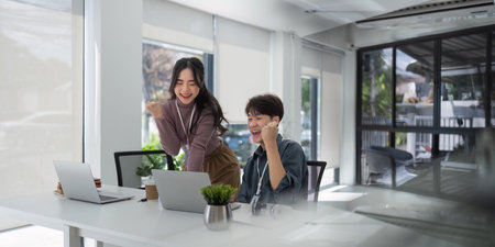 Two asian business raises her hands up rejoices in increasing profits in business. Business woman...