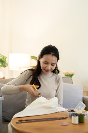 Woman repairs sews reuses fabric from old clothes economical reuse. DIY Hobby Reuse Recycling at homeの写真素材
