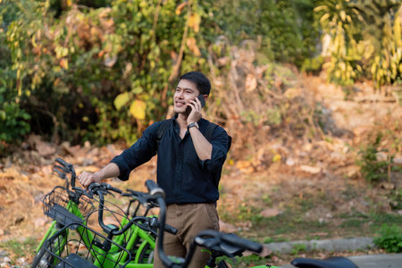 Eco friendly, Happy lifestyle asian young businessman ride bicycle go to office work at city street with bicycle in morningの写真素材