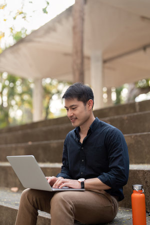 Asian businessman with reusable eco friendly ecological cup using laptop and sitting outside the...
