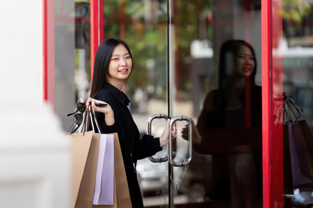 Cheerful Beautiful Asian woman holding shopping bags in shopping in the city on holiday Black Fridayの写真素材