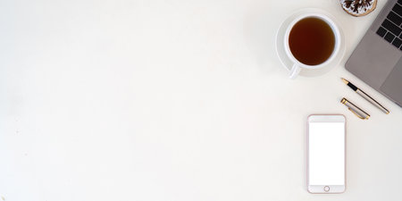 Top view smartphone with empty screen, Laptop and coffee cup on office desk. Copy space for your...