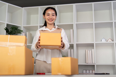 Young woman working online ecommerce shopping at her shop. Young woman sell prepare parcel box of...