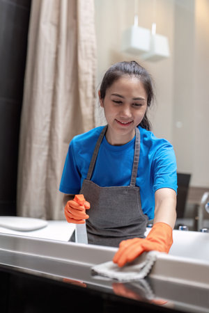 Professional cleaning service company employee in rubber gloves cleaning and detergent spray in...