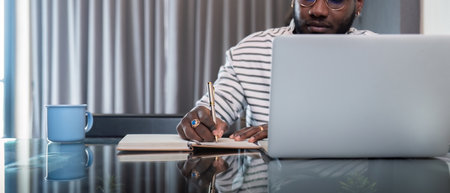 African American man working with laptop computer remote while sitting at glass table in living...