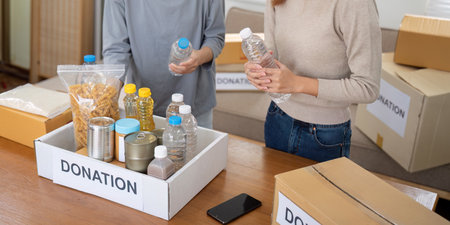 Group of volunteer woman working in home. Happy volunteer looking at food donation box separating...