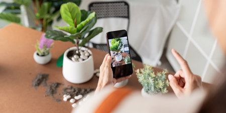 Hobby, young woman hand using mobile phone taking photo of pot, houseplant with dirt soil on table at homeの写真素材